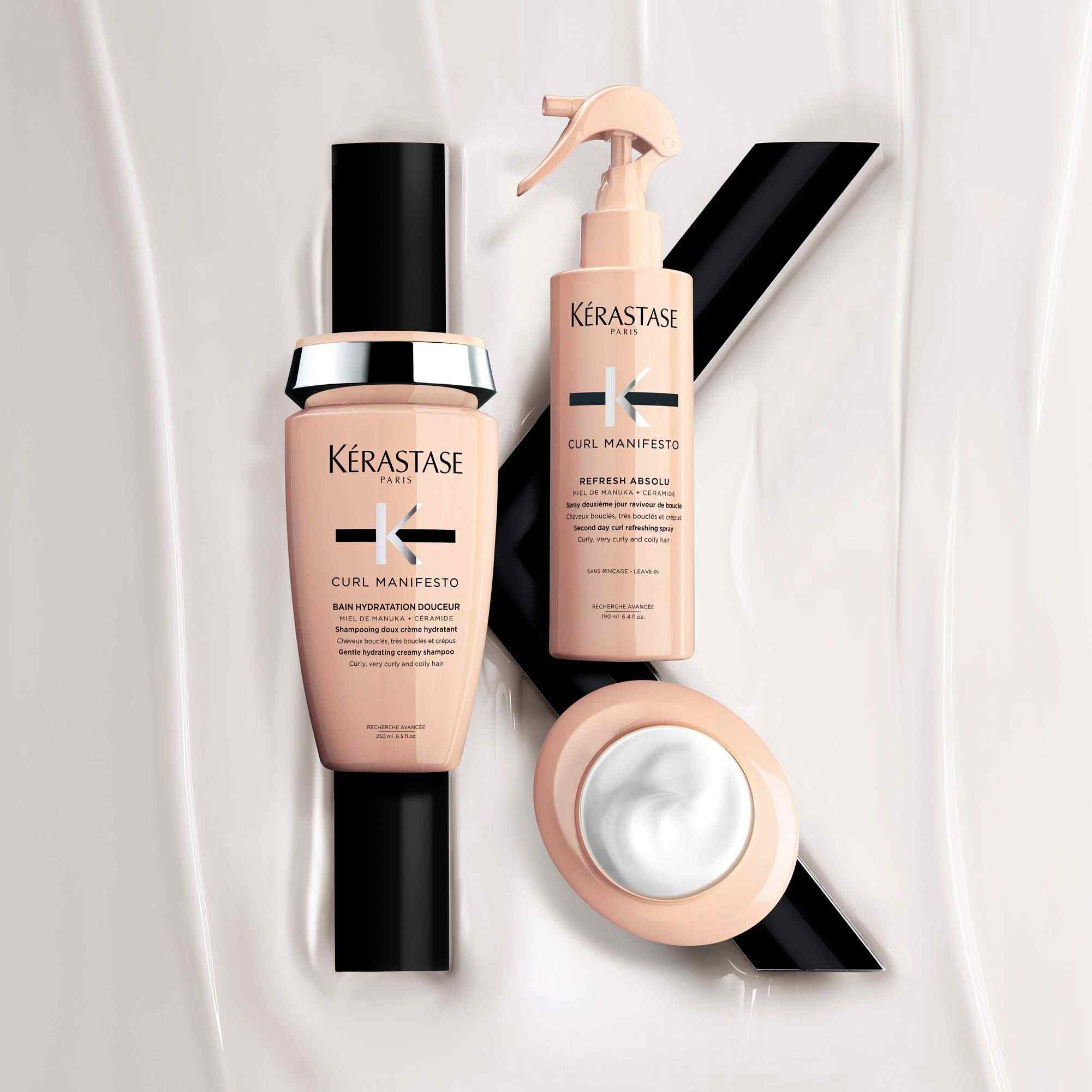 Due prodotti per capelli ricci Kérastase Curl Manifesto su uno sfondo di crema chiara e linee nere.